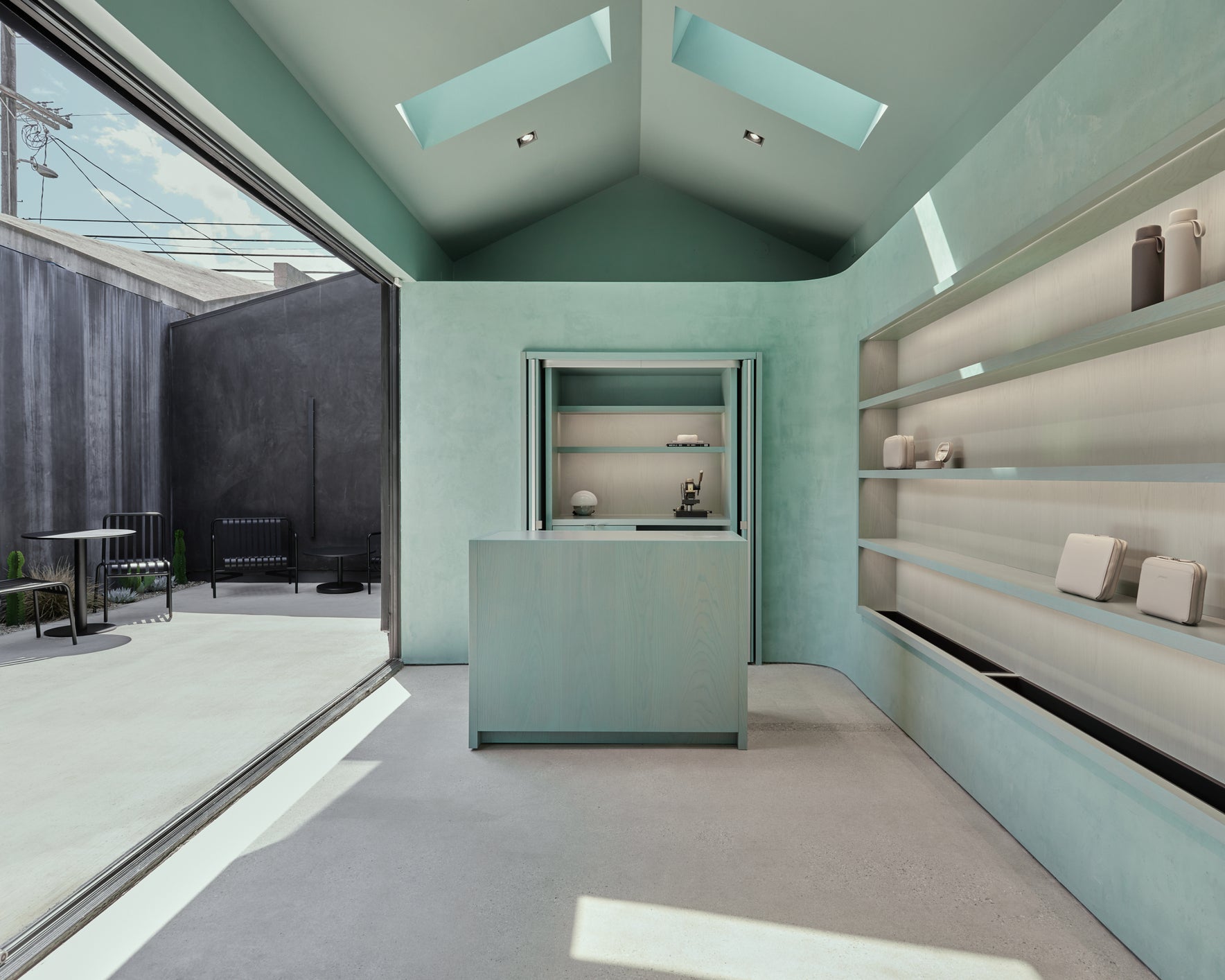 Modern interior design with green walls, glass ceiling panels, and shelves.