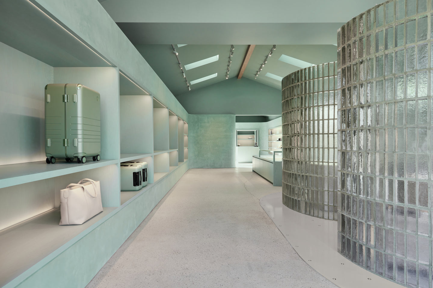 Modern interior with light green walls, glass block wall, and suitcases on shelves.
