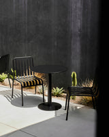 Black outdoor table with chairs against a dark wall