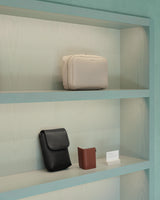 Three bags on a shelf against a light green wall