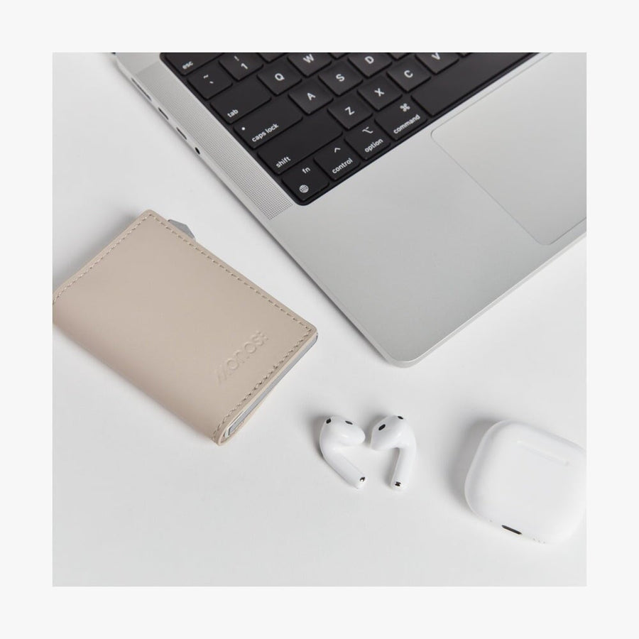 Ivory / Brushed Silver | Slim Wallet Pro in Ivory / Brushed Silver on a desk alongside wireless earbuds, and a laptop, highlighting its sleek and modern design in a lifestyle setting.