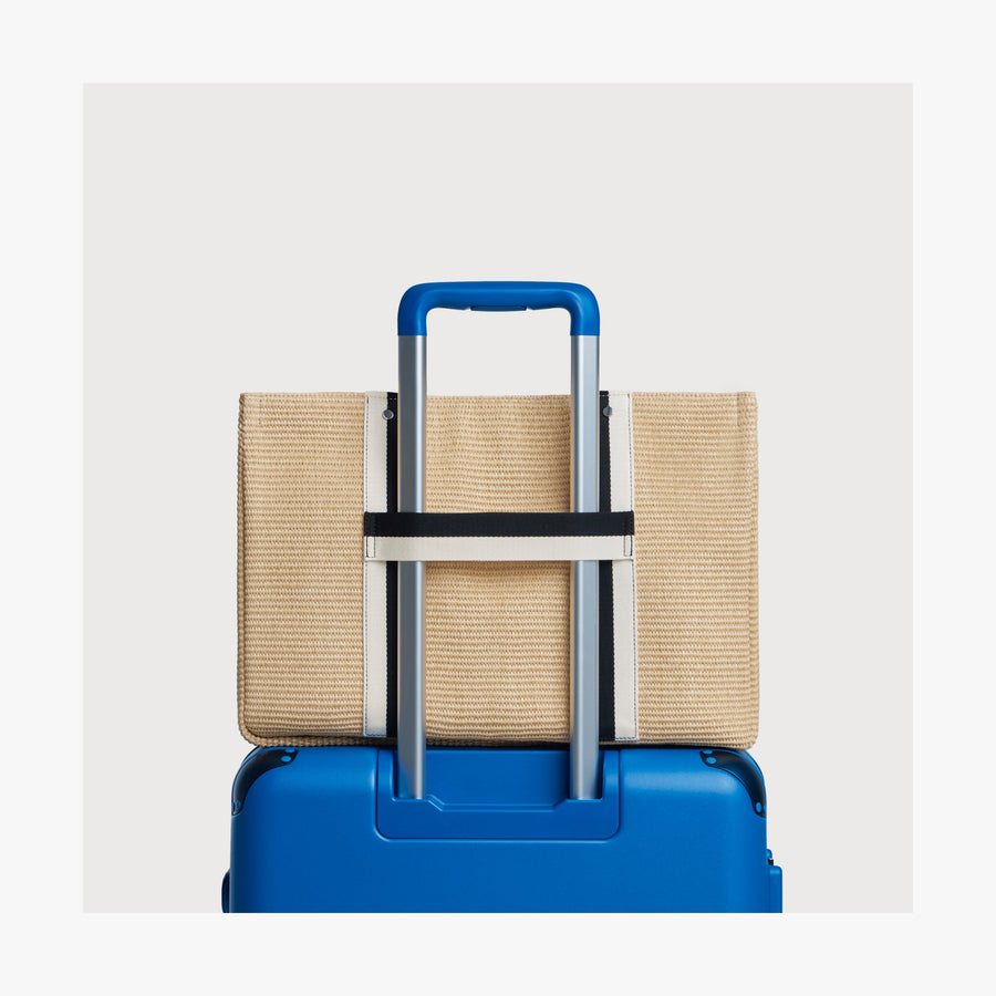 Natural | Canopy Tote securely placed over the telescopic handle of a Coastal Blue suitcase