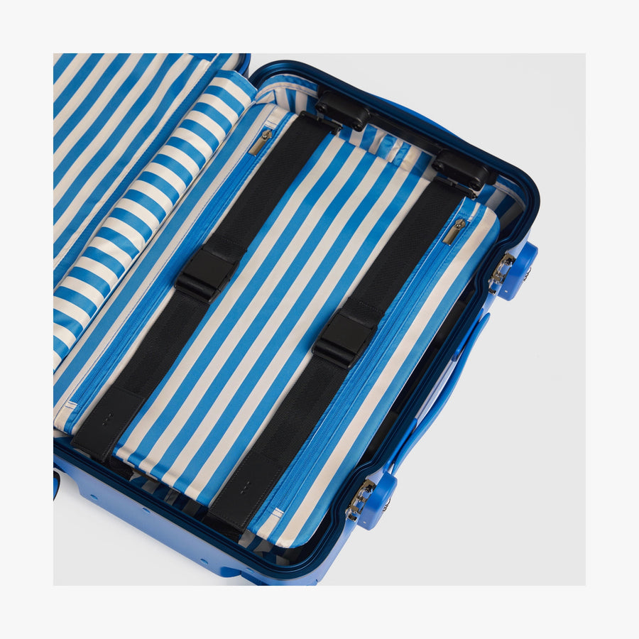 Coastal Blue | Interior view of a Hybrid suitcase in Coastal Blue featuring the Poplin Stripe Coastal Blue compression pad with adjustable straps