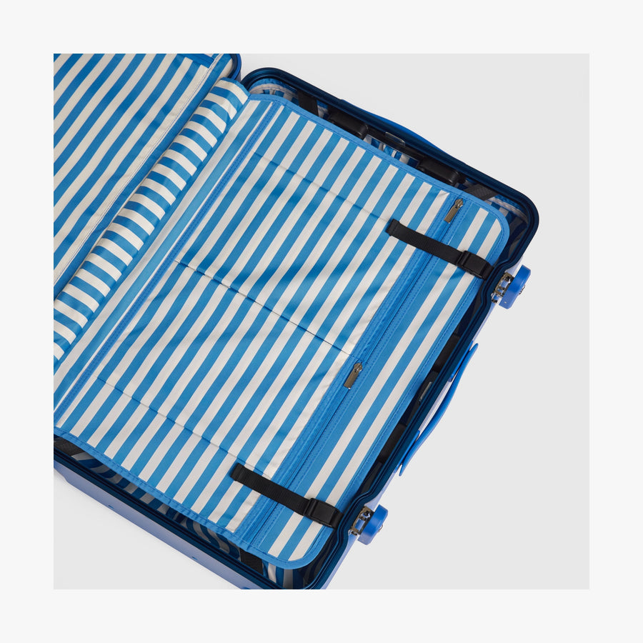 Coastal Blue | Interior view of a Hybrid suitcase in Coastal Blue featuring the Poplin Stripe Coastal Blue compression pad with adjustable straps