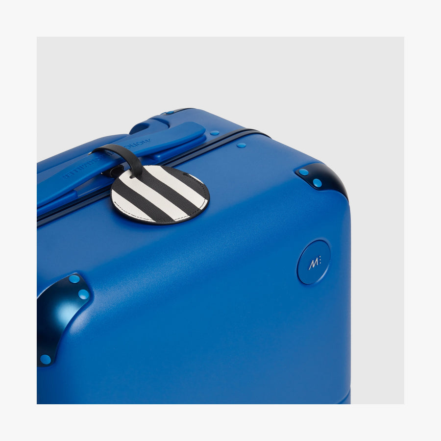 Coastal Blue | Close-up view of the logo detail on a Hybrid suitcase in Coastal Blue, paired with a Poplin Stripe Black luggage tag