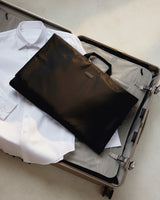 The Monos Garment Sleeve neatly packed inside an open suitcase — a sleek travel essential designed to keep suits and shirts wrinkle-free on the go.