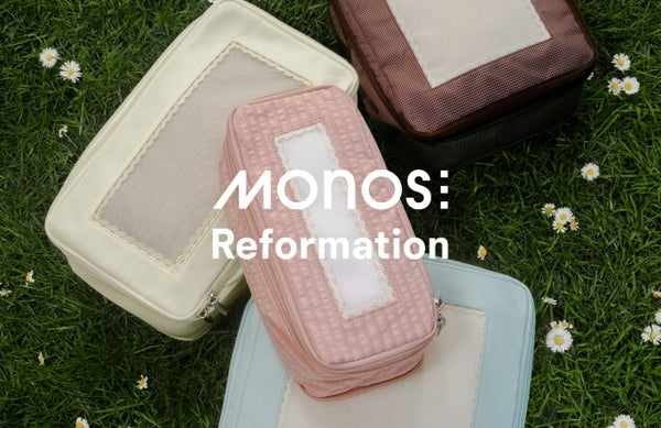 Monos x Reformation compressible packing cubes laid on a daisy-dotted grass field.